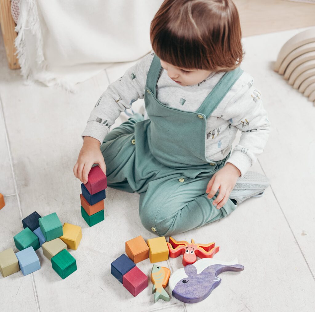 a child sitting on the floor playing with toys scaled