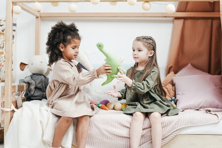 siblings playing a green plush toys